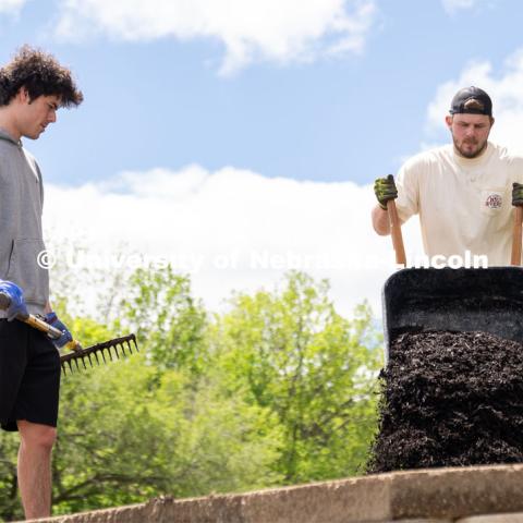 Pi Kappa Alpha’s Grant Breidenbach waits for Ethan Heinemann to supply more mulch for him to spread out at the Van Dorn Villa Retirement Living complex during the Big Event. May 4, 2024. Photo by Kirk Rangel for University Communication.